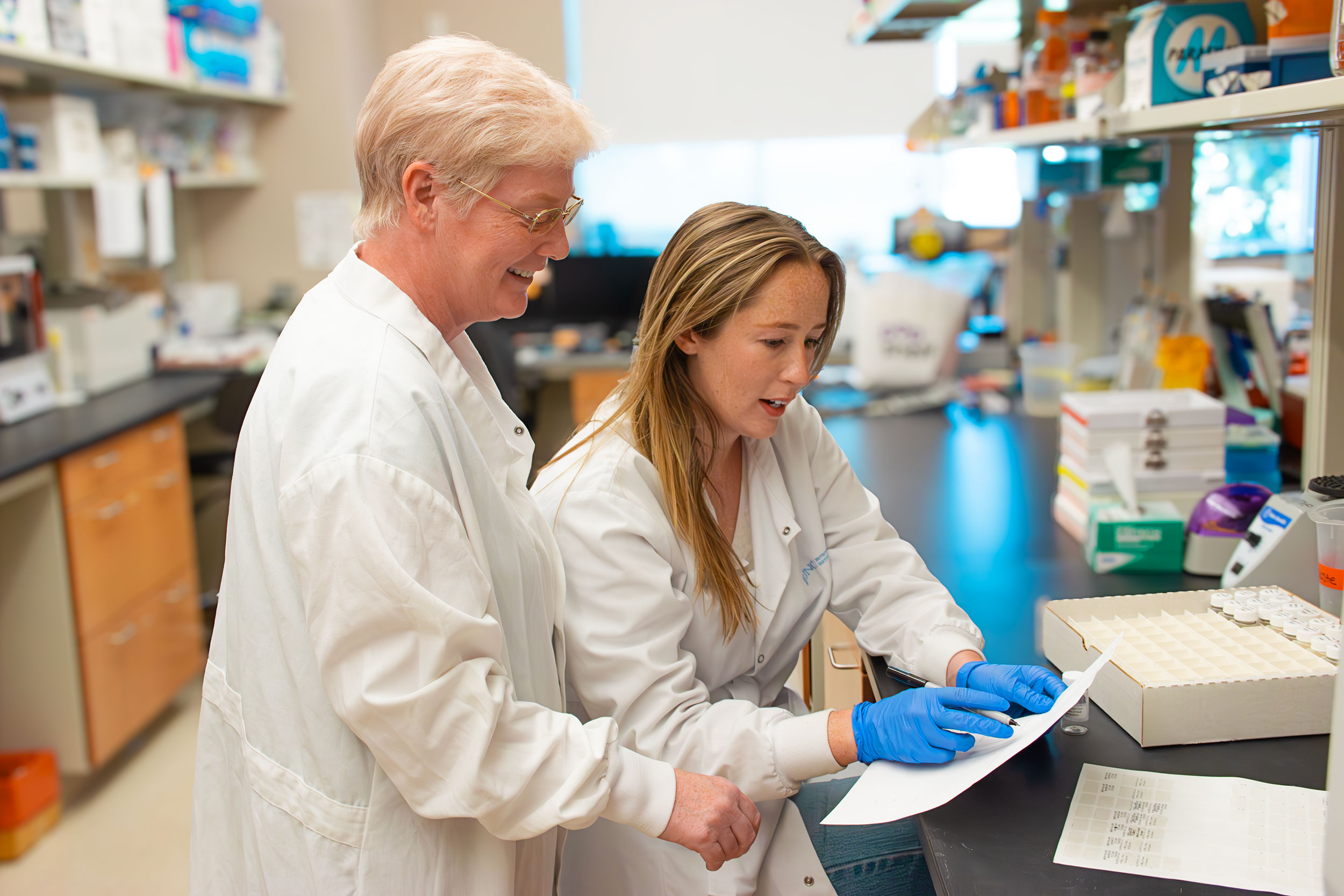Hannah-and-Sandra-Paper-Side-Angle Sandra M. Mooney, PhD and Hannah Petry looking over lab results